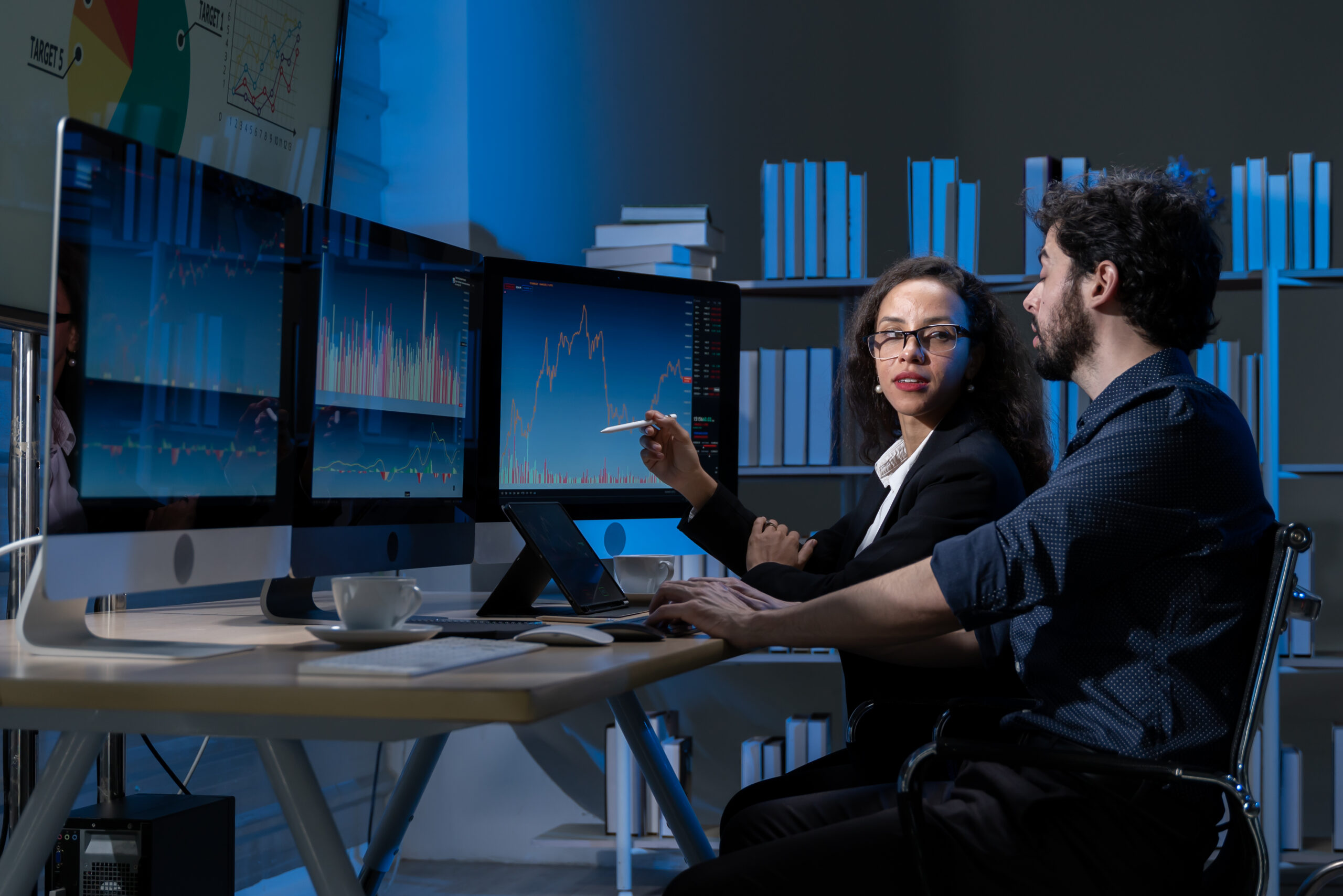 business men and women who are working hard Working late into the night to complete tasks according to set goals The two of them looked at the company's financial graph attentively.